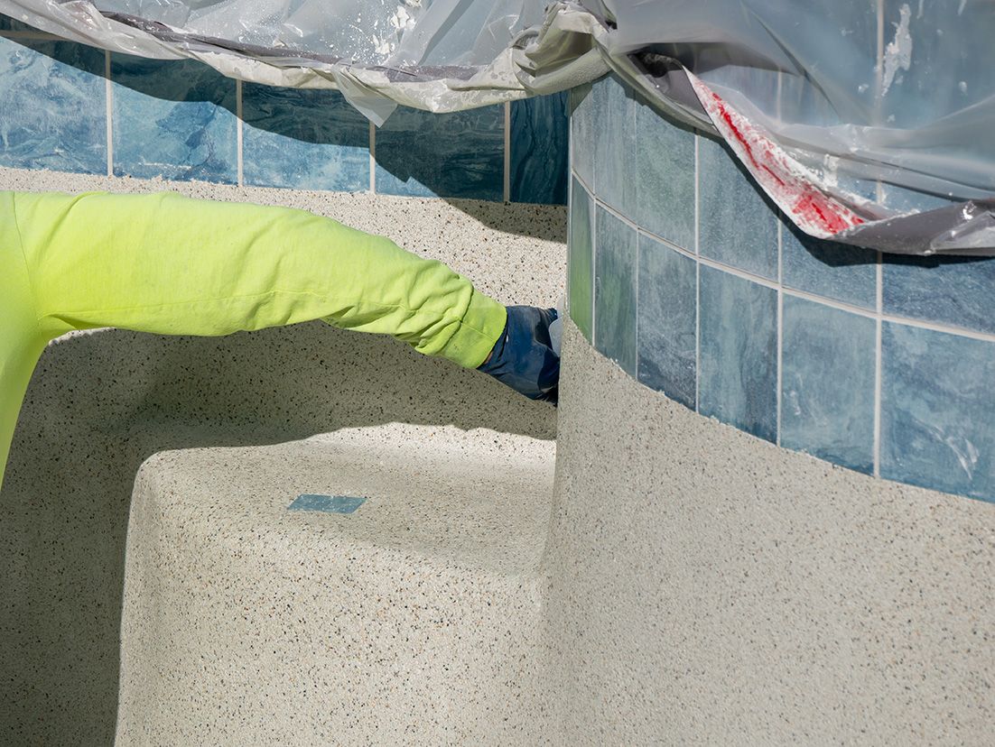 A person in a yellow shirt is working on a swimming pool.